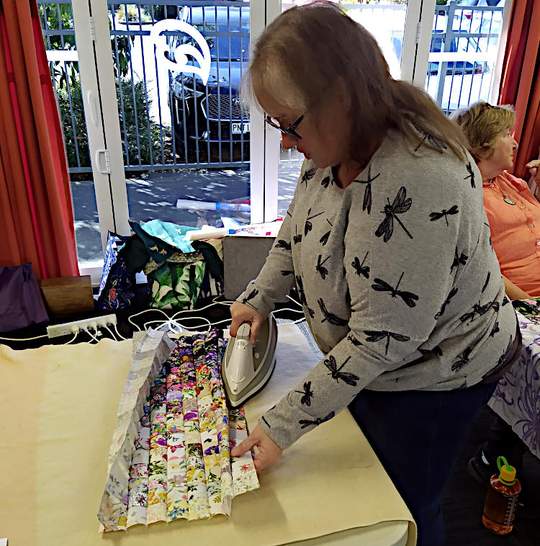 Sandy ironing the back of her sewn together squares